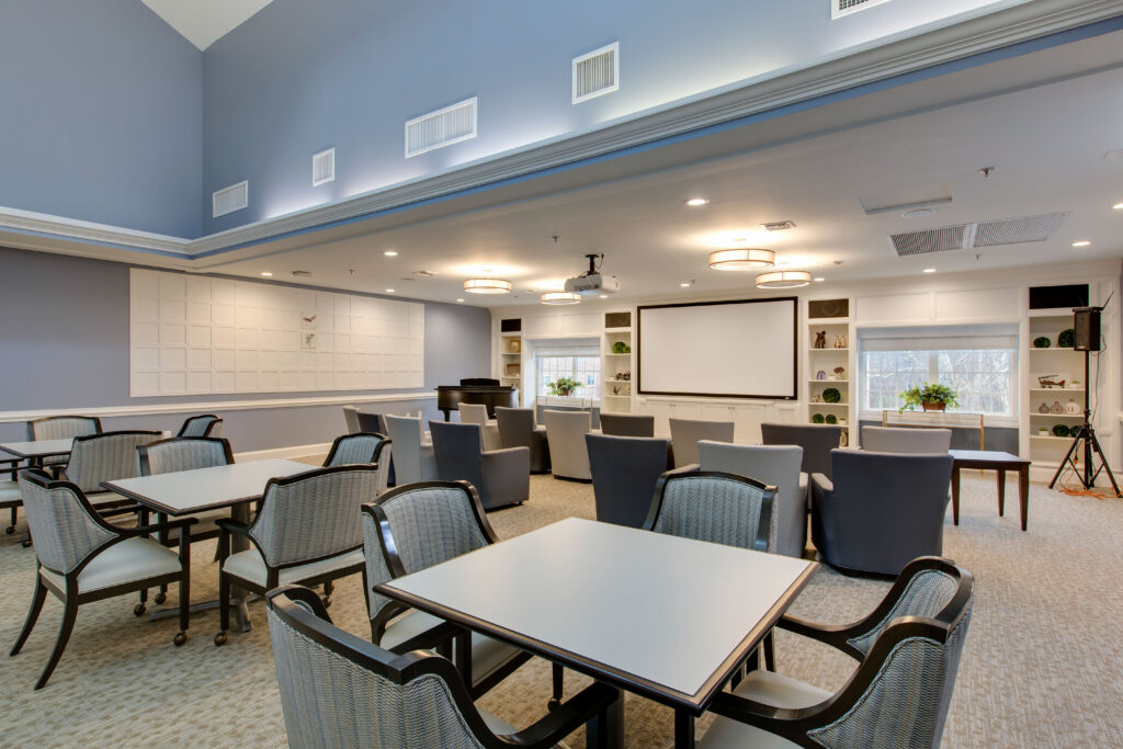 Community gathering room with dining seating and a projector and media seating