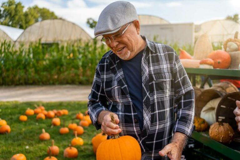 Senior man picking out a pumpkin at a pumkin patch