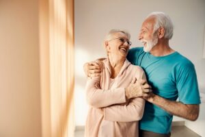 Couple of older adults hugging and smiling at each other