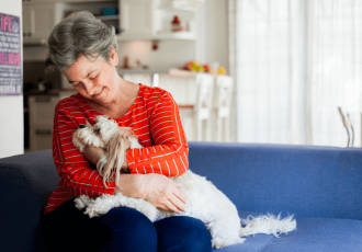 A woman on a couch holding her dog